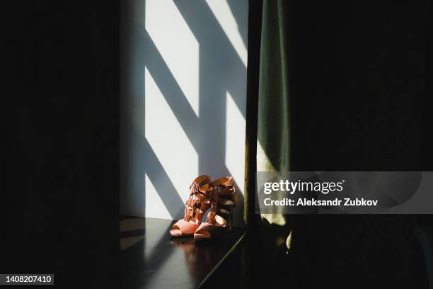 designer wedding shoes of the bride on a wooden windowsill, on a sunny day. women's new modern fashion high-heeled shoes made of genuine leather. morning preparations for the wedding. - alta moda fotografías e imágenes de stock