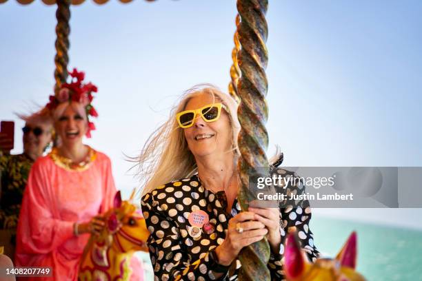 older lady dressed in colourful clothes riding a carousel - fahrgeschäft stock-fotos und bilder