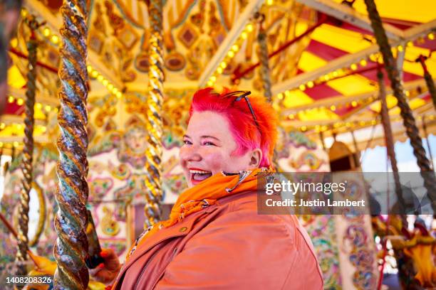 woman with colourful hair laughing on a carousel - fahrgeschäft stock-fotos und bilder