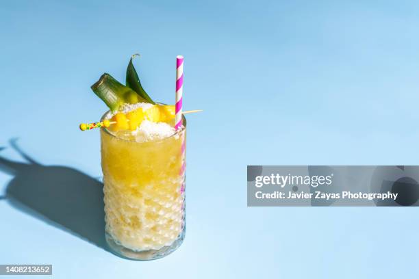 pina colada (pineapple smoothie) on blue background - yellow smoothie stock pictures, royalty-free photos & images