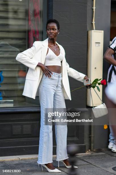 Guest wears diamonds earrings, a silver long chain with embroidered diamonds butterfly necklace, a white V-neck / cropped top, a white oversized...