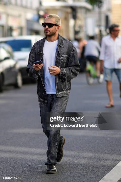 Guest wears black sunglasses, a white t-shirt, a black faded denim jacket, matching black faded denim large pants, black shiny leather derbies shoes,...