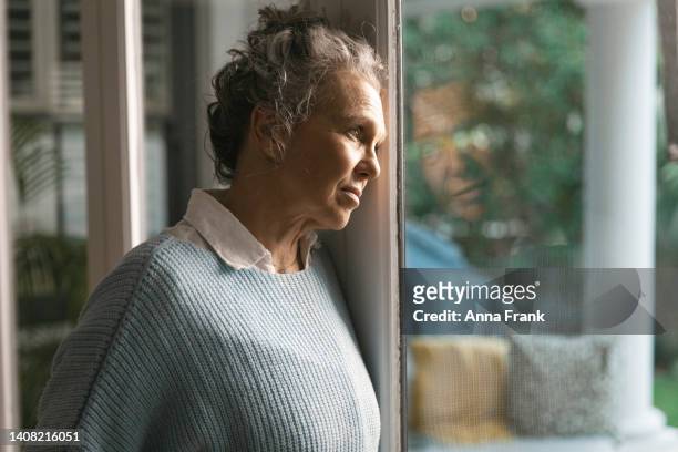 woman looking out of the window - autumn sadness stock pictures, royalty-free photos & images