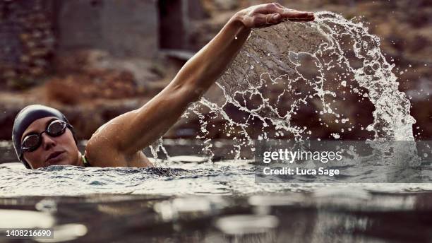 water splashes caught in motion with a female swimmer enjoying a sunset sea swim - still life stockfoto's en -beelden