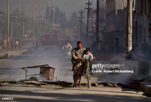 An unidentified man walks with a child riding a bike July 27, 1993 in Jammu and Kashmir, India. Kashmir has been partitioned between India and...