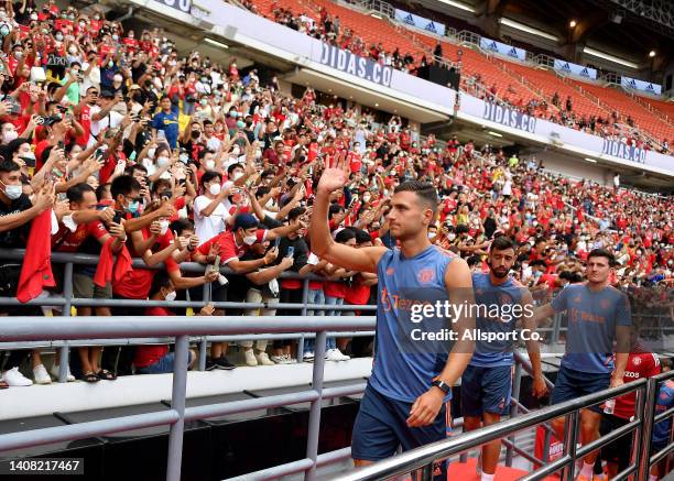 Diogo Dalot, Bruno Fernandes and Harry Maguire of Manchester United enter the stadium as fans cheer during their open training session at the...
