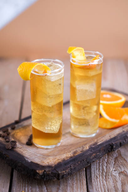 ice tea drink cocktail with orange zest in longdrink glass - orange cocktail stock pictures, royalty-free photos & images