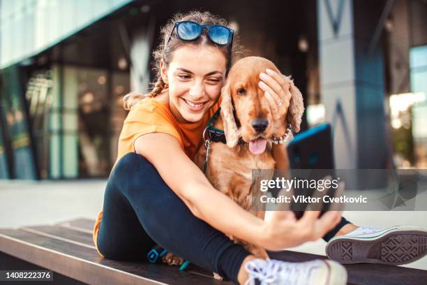 cute girl and her dog taking selfies and having fun in the city - woman dog bench stock pictures, royalty-free photos & images