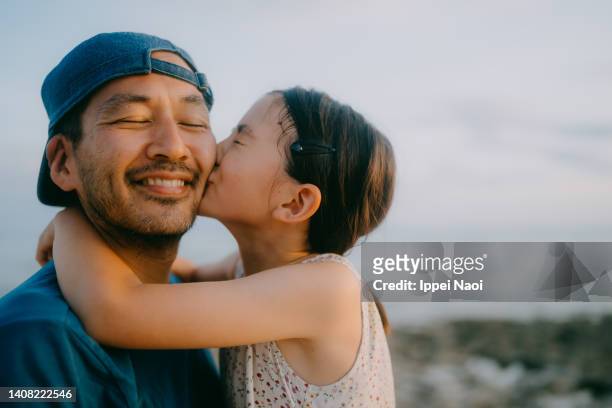 young daughter kissing her father on beach - midden oosterse etniciteit stockfoto's en -beelden