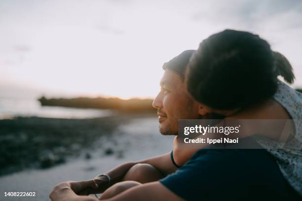 young daughter embracing her father from behind on beach - person of color stock pictures, royalty-free photos & images