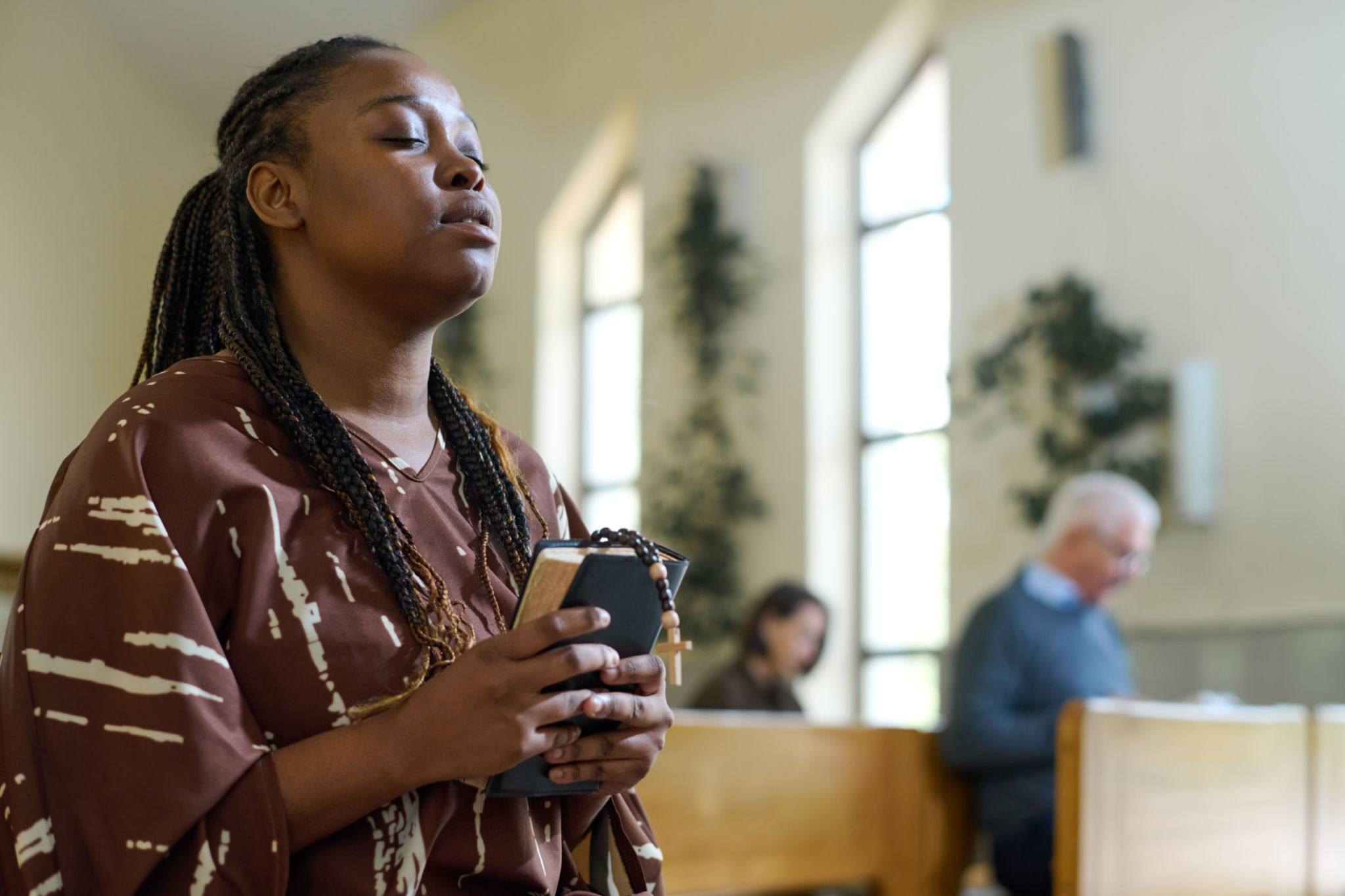 Young black woman in casual dress keeping her eyes closed during prayer Young black woman in casual dress keeping her eyes closed during prayer