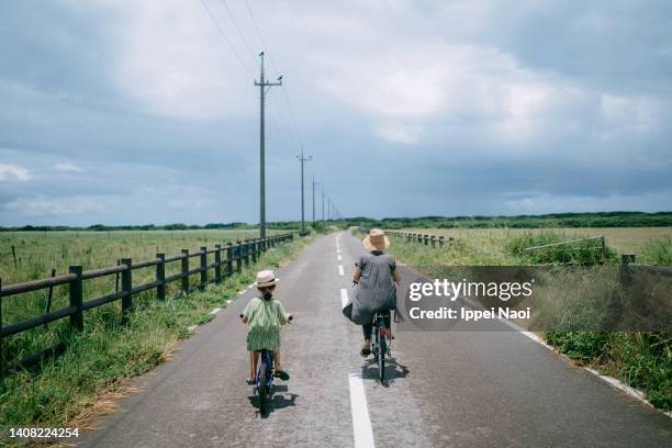 mother and child riding bicycle through farmland, japan - kyushu stock-fotos und bilder