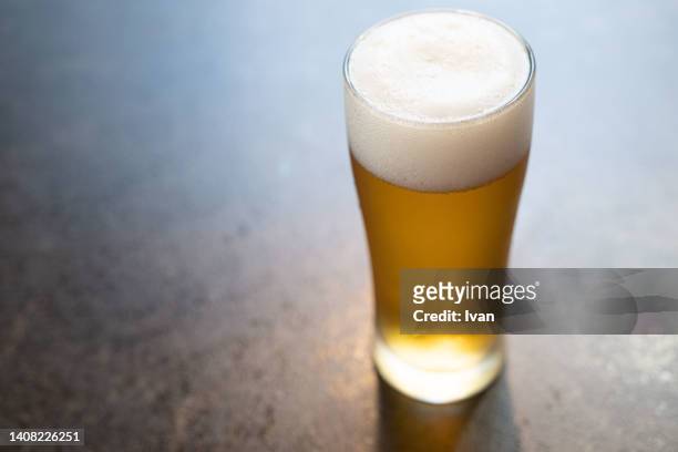glass of beer on wooden table - lager stock pictures, royalty-free photos & images