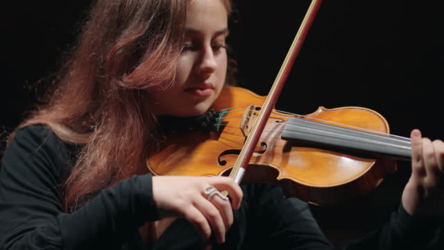 young female fiddler is learning to play violin or viola in philharmonic hall