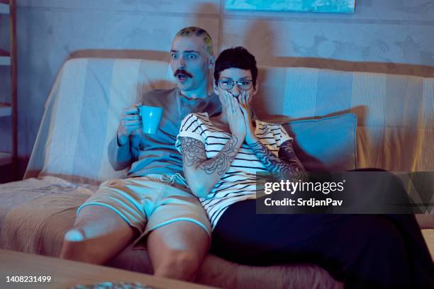 woman covering her mouth with hand while watching a scary movie with boyfriend - woman watching horror movie stock pictures, royalty-free photos & images