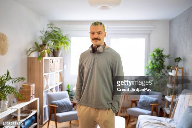 retrato de um jovem urbano com cabelo tingido e bigode em pé orgulhosamente em seu quarto - modern manhood - fotografias e filmes do acervo