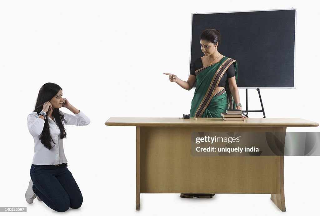 Female teacher punishing a student in a classroom