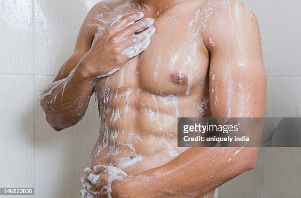 mid section view of a man taking a shower - bauchmuskel stock-fotos und bilder