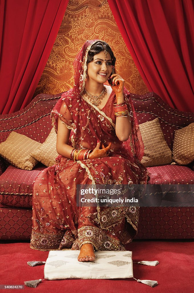 Bride in traditional wedding dress and talking on a mobile phone