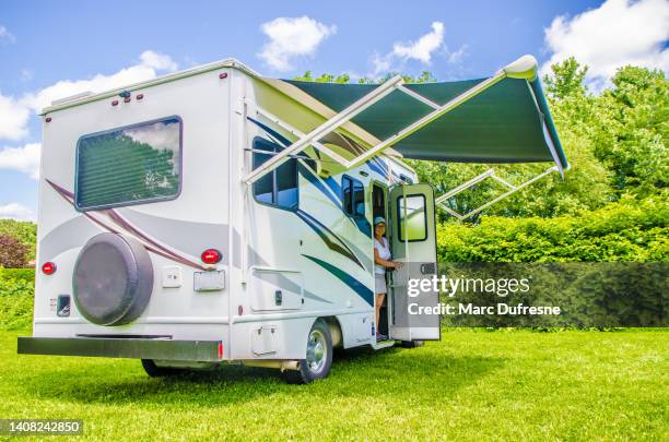 mujer saliendo de una pequeña autocaravana clase c en el césped - toldo estructura de edificio fotografías e imágenes de stock