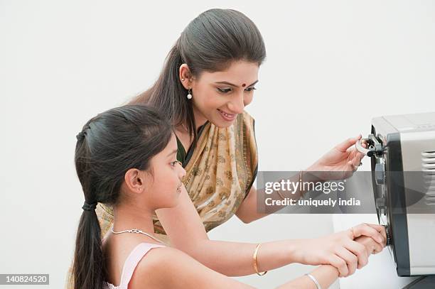 girl operating microwave oven with the help of her mother - microwave stock pictures, royalty-free photos & images