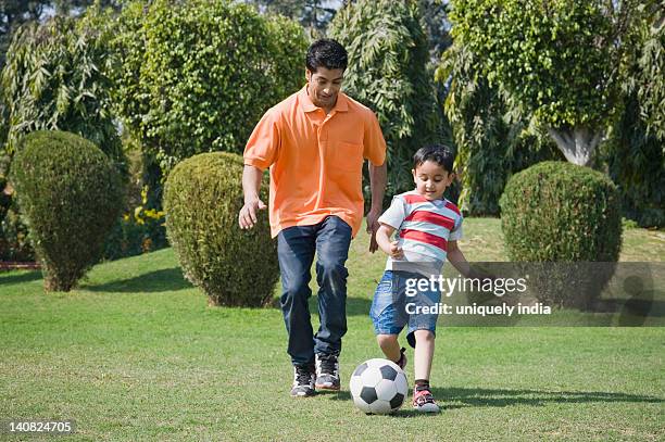 man and his son playing with a soccer ball, gurgaon, haryana, india - indian football stock pictures, royalty-free photos & images