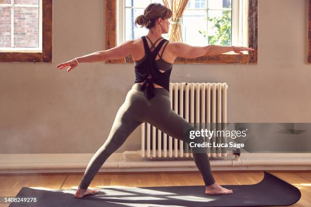 athletic female practicing yoga in a sunny yoga studio - legging stock pictures, royalty-free photos & images