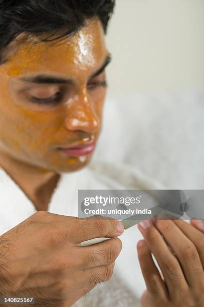 close-up of a man with peel off mask filing his nails - peel off mask stock-fotos und bilder