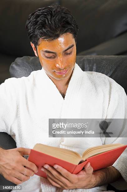 man with peel off mask reading a book - peel off mask stock-fotos und bilder