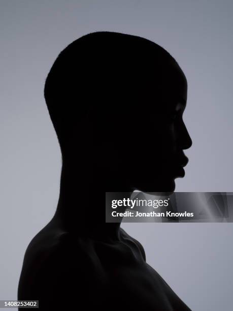 silhouetted profile of woman with shaved head - shaved head ストックフォトと画像