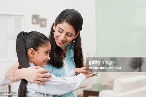 woman giving a glass of milk to her daughter - glass of milk stock pictures, royalty-free photos & images