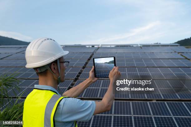 male electrician taking photo of solar power plant - low carbon technology stockfoto's en -beelden