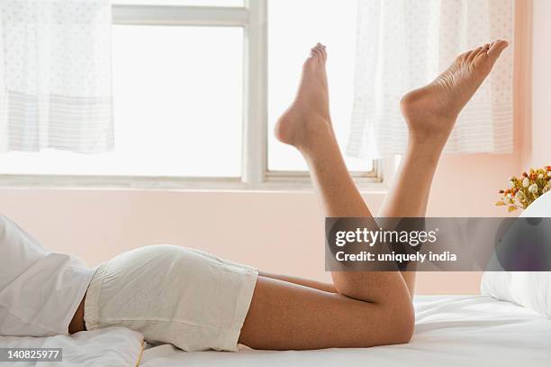 low section view of a woman lying on the bed - woman lying on stomach with feet up foto e immagini stock