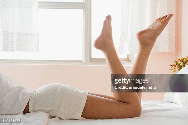 low section view of a woman lying on the bed - woman lying on stomach with feet up stock pictures, royalty-free photos & images