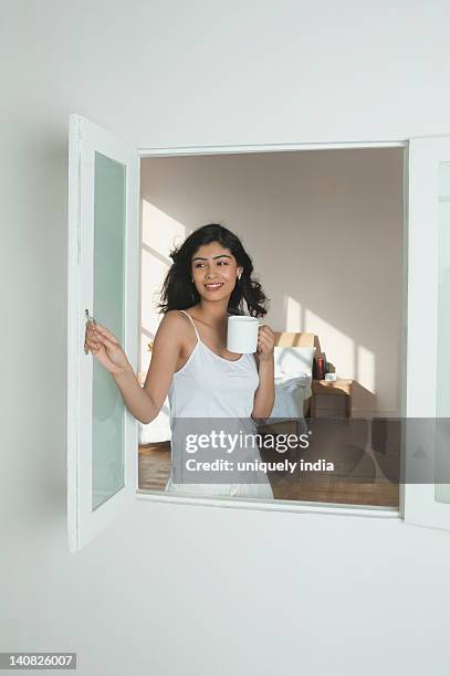 woman holding a cup of coffee and smiling - キャミソール ストックフォトと画像