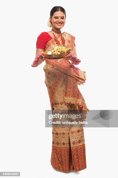 portrait of a woman holding a plate of religious offerings on bihu festival - bihu stock pictures, royalty-free photos & images