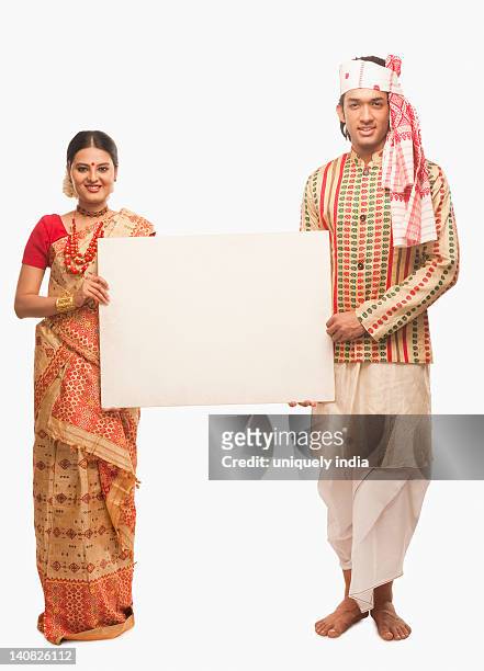 portrait of a couple in traditional clothing holding a blank placard - bihu stock pictures, royalty-free photos & images