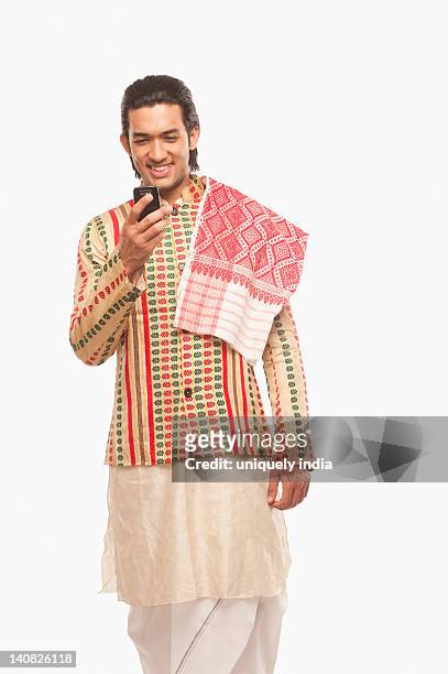 man operating a mobile phone in traditional clothing - bihu stock pictures, royalty-free photos & images