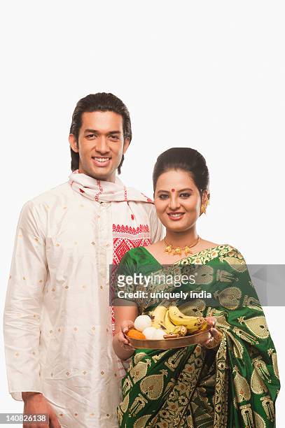 portrait of a couple smiling with a plate of religious offerings on bihu festival - bihu stock pictures, royalty-free photos & images