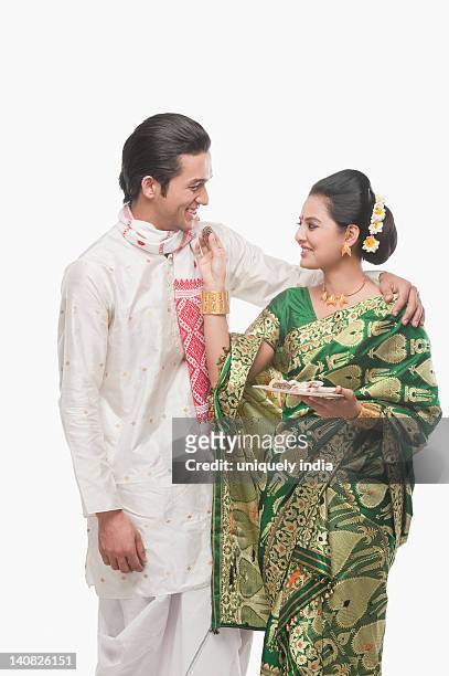 woman feeding prasad to a man on bihu festival - bihu stock pictures, royalty-free photos & images