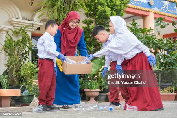 side view of school student and teacher cleaning the school from plastic garbage - picking up garbage stock pictures, royalty-free photos & images