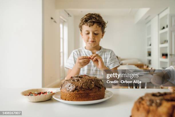 boy decorating his birthday cake - decorating a cake stock pictures, royalty-free photos & images