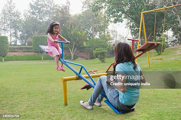 woman with her daughter playing on a seesaw - see saw fotografías e imágenes de stock