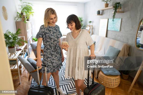 caucasian female friends booking uber via mobile app, ready to leave for their trip - hostel people stock pictures, royalty-free photos & images