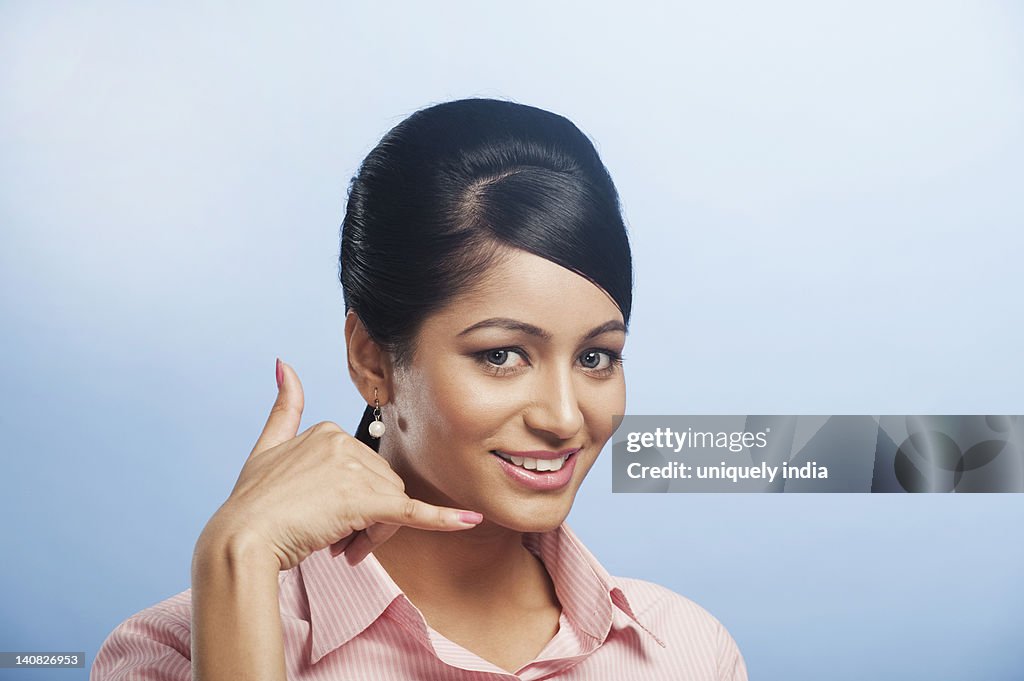 Woman making call me gesture and smiling