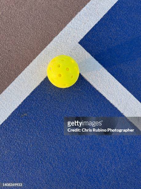 a pickleball landing in bounds on a blue court - ベースライン ストックフォトと画像