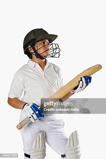 boy in cricket uniform holding a cricket bat - baseball helmet stockfoto's en -beelden