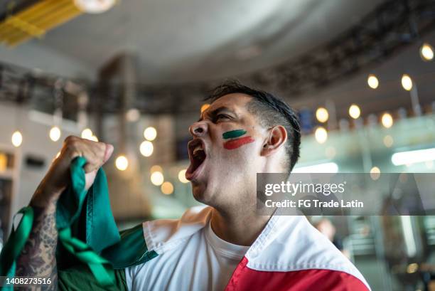 hombre adulto medio celebrando un gol en el bar - fiesta mexicana fotografías e imágenes de stock