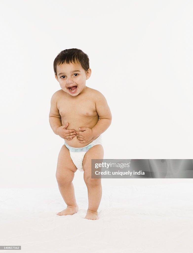 Baby boy standing on bed and laughing