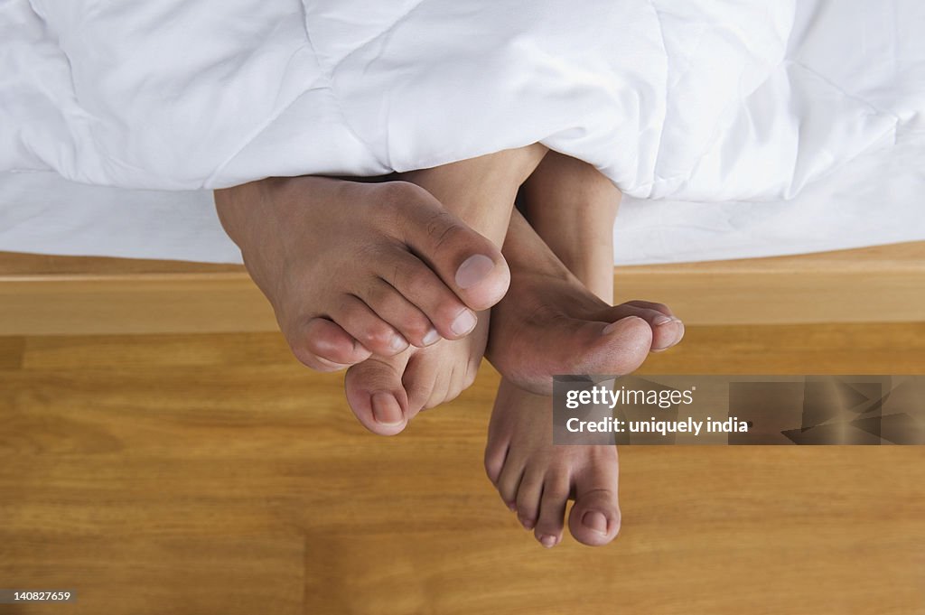 Couple's feet sticking out from a bed
